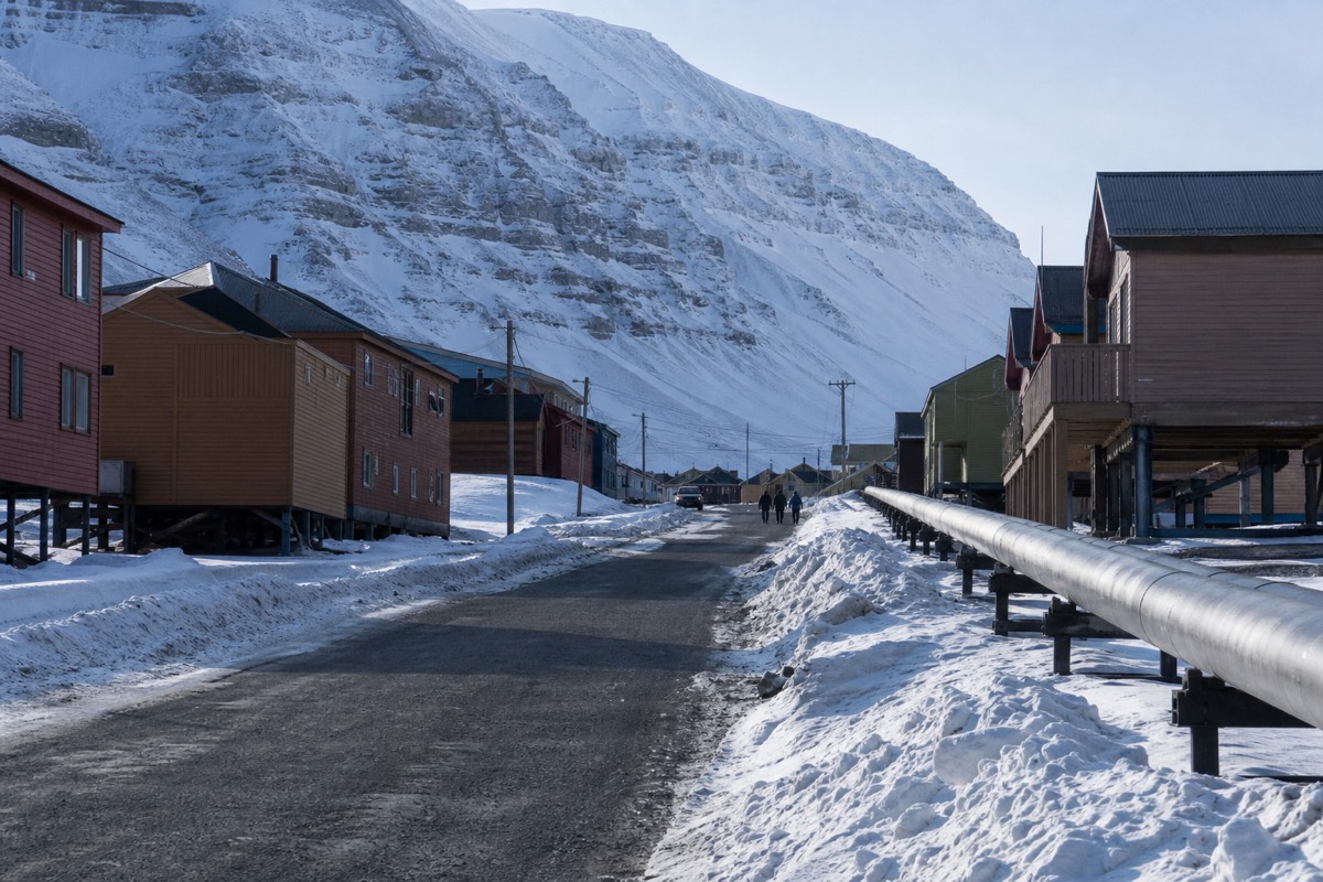 Main street of Longyearbyen with coloured timber buildings on stilts and mountains behind