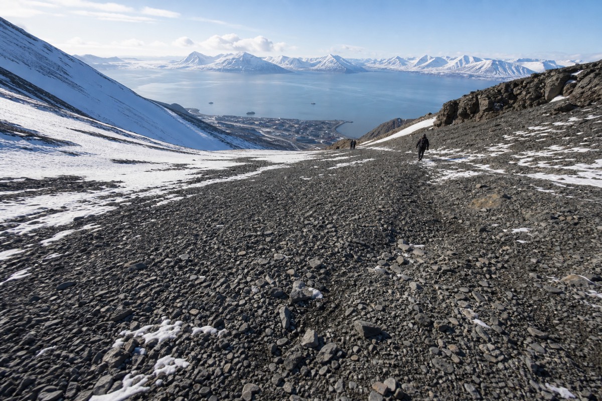 Walkers on the flat plateau of Platafjellet looking down over Longyearbyen and Adventfjorden