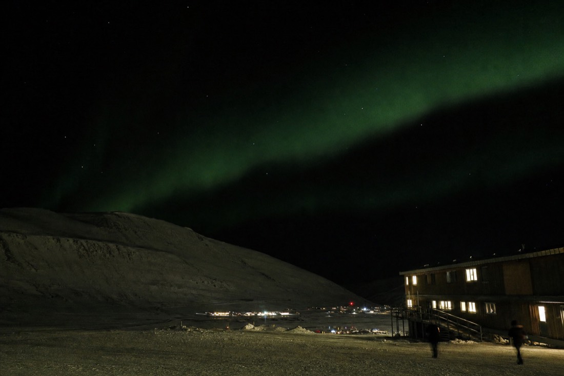 Green aurora over the snow-covered valley outside Longyearbyen during the Svalbard polar night