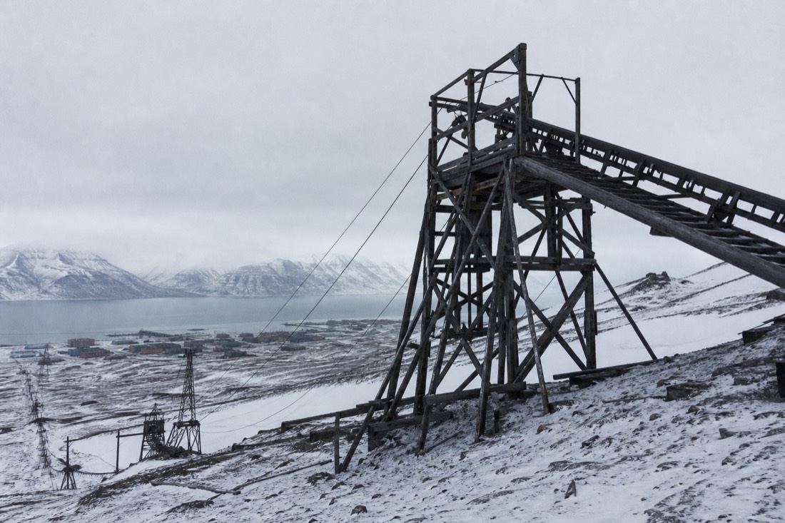 Timber headframe and conveyor of a disused Longyearbyen coal mine against a snow slope