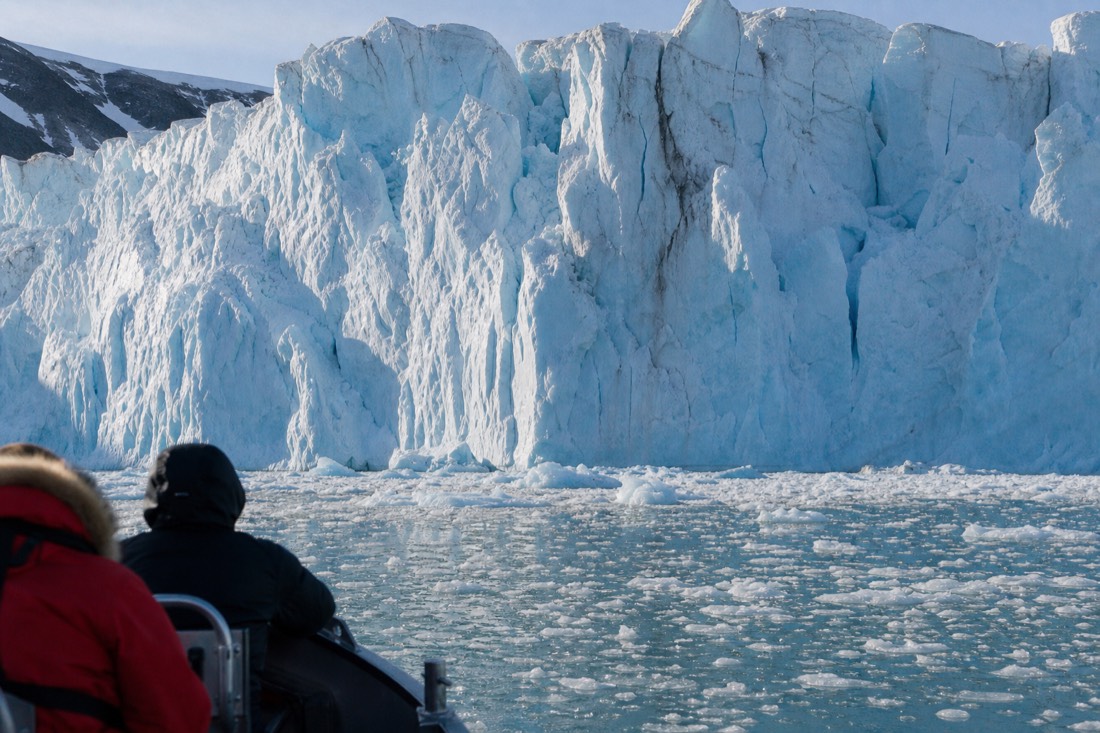 Small expedition boat at the calving front of a tidewater glacier on a Svalbard boat tour