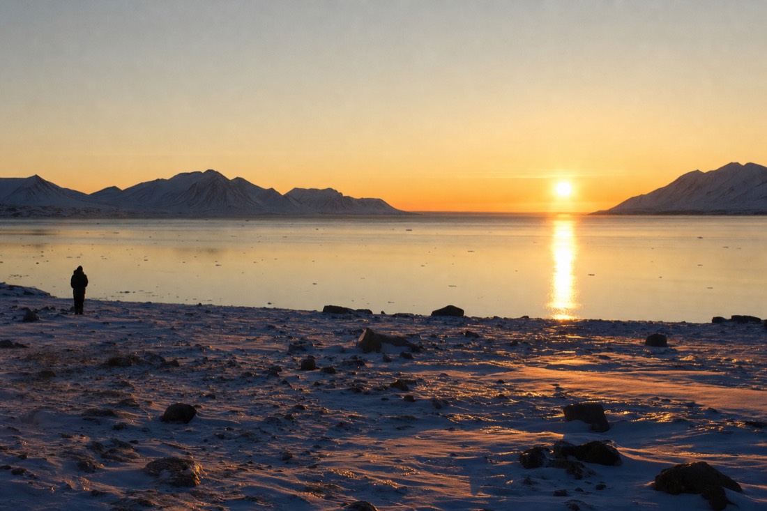 Midnight sun low over Isfjorden casting long gold light across still Arctic water