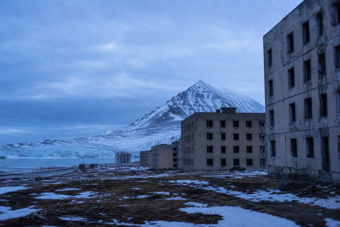 Abandoned Soviet apartment blocks at Pyramiden with the Nordenskiold glacier behind, reached on a Svalbard boat tour